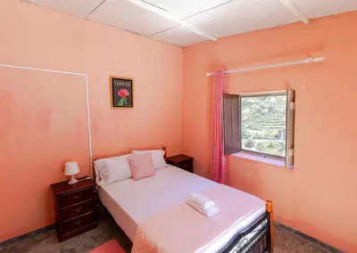 a bedroom with a bed and a window and a mirror at Quinta Toca do leão in Ribeira Grande