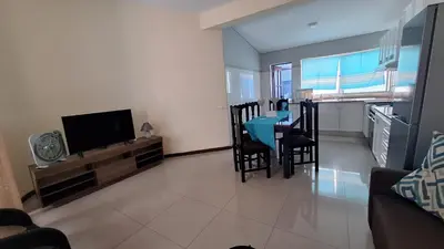 a living room with a dining room table and a television at Diva Apartamento in Praia