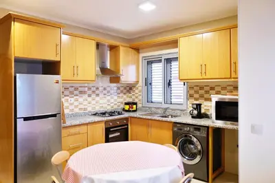 a kitchen with wooden cabinets and a washer and dryer at Private Apartament Celestina & Carlos in Mindelo