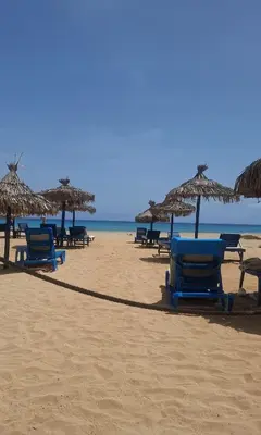 a group of chairs and umbrellas on a beach at Luxury Lux Studio with Seaview in Santa Maria