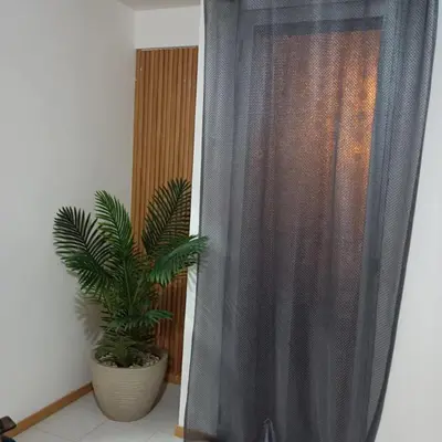 a shower with a curtain next to a plant at ManubelaRelax in Praia