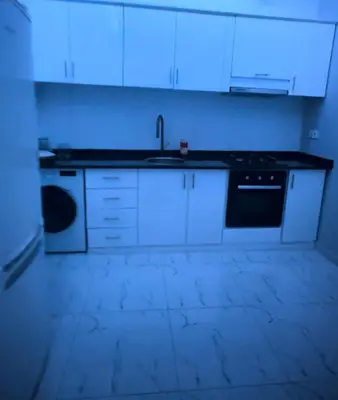 a kitchen with white cabinets and a sink and a stove at Apartamento T2 mobiliado in Mindelo
