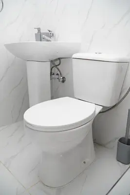 a white bathroom with a toilet and a sink at Comfortable 1-bedroom 400 meters from the beach with Fast Wi-Fi in Santa Maria