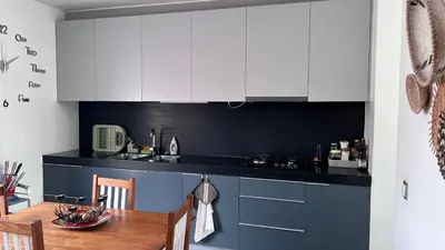 a kitchen with white cabinets and a wooden table at City View Apartment in Praia