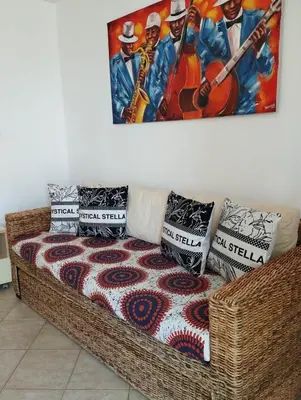 a wicker couch with pillows and a painting on the wall at Holiday Properties Tres Caravelas in Santa Maria