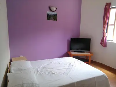 a bedroom with a purple wall with a bed and a television at Damontanha in Ribeira Grande