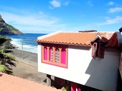 a white building with pink windows next to the ocean at Black Mamba in Paul