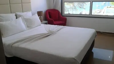 a bedroom with a white bed and a red chair at Vista Mar in Tarrafal