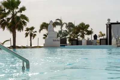 a swimming pool with palm trees in the background at Hotel LIVVO Budha Beach in Santa Maria