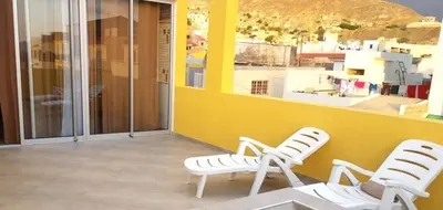 two white chairs sitting next to a yellow wall at Basic Hotel in Mindelo