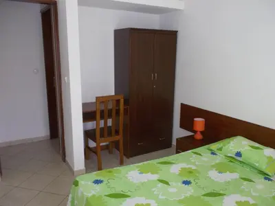a bedroom with a bed and a desk and a cabinet at Basic Hotel in Mindelo