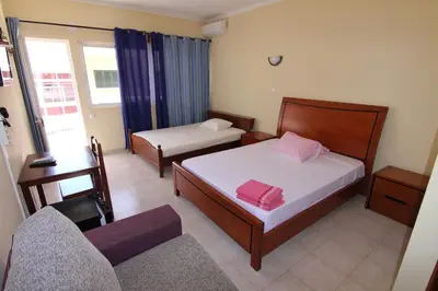 a bedroom with a bed and a couch and a chair at Restaurante Residencial Nova Cidade in Porto Novo