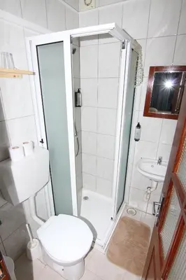 a small bathroom with a toilet and a shower at Restaurante Residencial Nova Cidade in Porto Novo