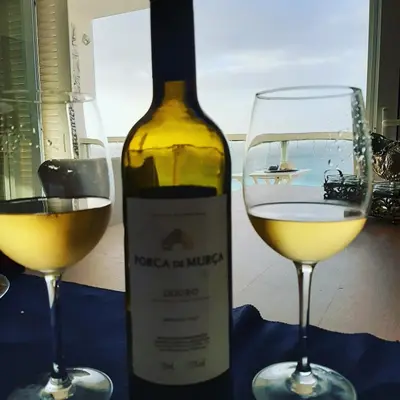 a bottle of wine next to two glasses of white wine at @Georgette in Mindelo