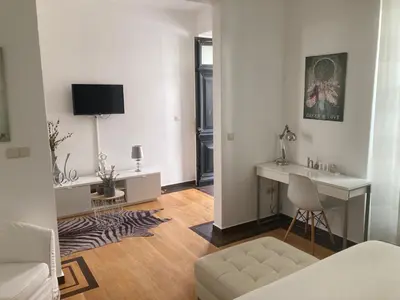 a living room with a couch and a desk and a television at Casa Senador in Mindelo
