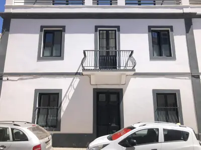 a white house with two cars parked in front of it at Casa Senador in Mindelo