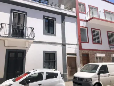 two cars parked in front of a white building at Casa Senador in Mindelo