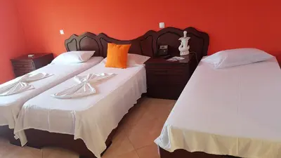 two twin beds in a room with red walls at Hotel Ocean View & Restaurante Seafood in São Filipe
