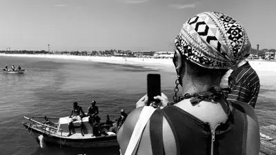 a woman taking a picture of a boat in the water at Sal Apartments Djadsal Moradias in Santa Maria