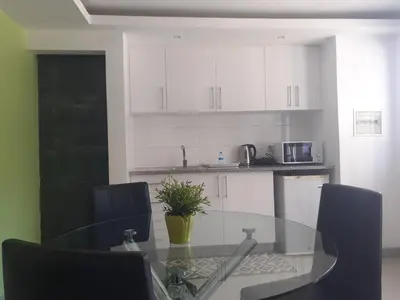 a kitchen with a glass table and black chairs at Apto T1 Comfort in Praia