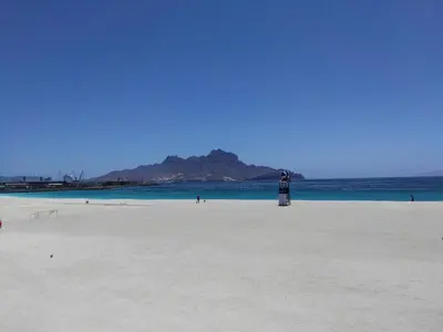 a lighthouse on a beach with a mountain in the background at Casa da Luz - Appartement in Mindelo