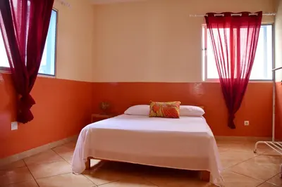 a bedroom with red curtains and a white bed at Meeting Point Hostels-Tarrafal Center, also in Praia & Fogo-NO CASH ACCEPTED in Tarrafal