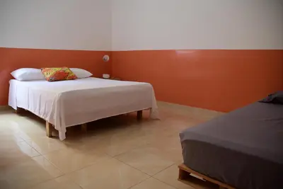 a bedroom with a bed and a red wall at Meeting Point Hostels-Tarrafal Center, also in Praia & Fogo-NO CASH ACCEPTED in Tarrafal