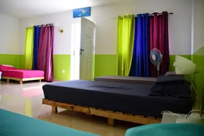 a room with two beds and colorful curtains at Meeting Point Hostels-Tarrafal Center, also in Praia & Fogo-NO CASH ACCEPTED in Tarrafal