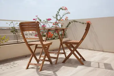 a wooden chair and table with flowers on a balcony at Ca Marta Penthouse in Sal Rei