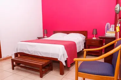 a bedroom with a bed with a pink wall at Pousada Quinta Ribeirinha in Cidade Velha