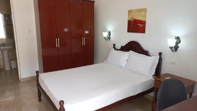 a bedroom with a white bed with a wooden headboard at Hotel Savana in São Filipe