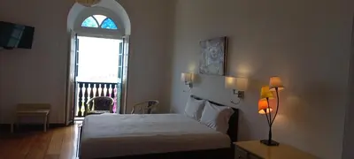 a bedroom with a bed and an arched window and a window at Hotel Savana in São Filipe