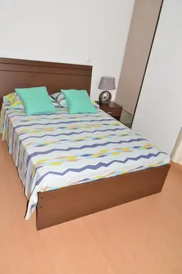 a bedroom with a large bed with green and blue pillows at Apartamento Augusto in Praia