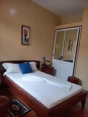 a bedroom with a large bed with a blue pillow at Pensao Mille Nuits in Tarrafal