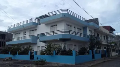 a white building with blue balconies on it at Casa Mendes in Tarrafal