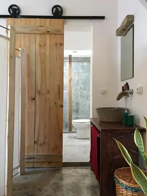 a bathroom with a wooden door and a toilet at Casa Pau in Santa Maria