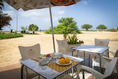 a table and chairs on the beach with an umbrella at Ouril Hotel Agueda in Sal Rei