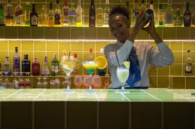 a woman standing behind a bar with some cocktails at Hotel Dunas de Sal in Santa Maria