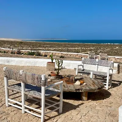 a wooden table and two chairs and a table and a table and benches at Spinguera Ecolodge in Espingueira
