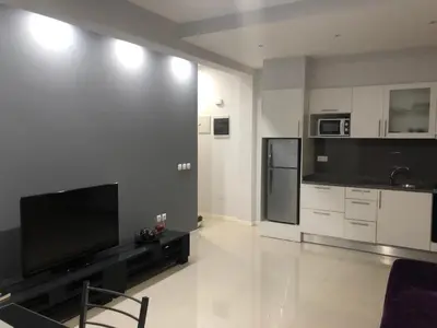 a large living room with a television and a kitchen at T1 Família Luz in Mindelo