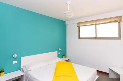 a bedroom with blue walls and a bed with a yellow bench at Apartamento Las Rochas in Mindelo