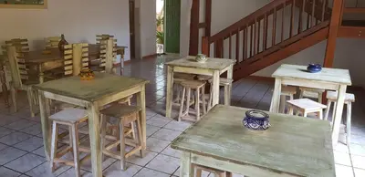 a group of tables and stools in a room at Surf House Hostel in Santa Maria