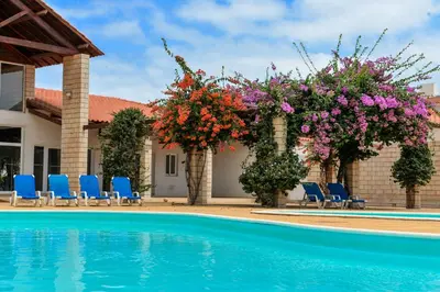 a pool with chairs and flowers next to a house at Guesthouse Le Châtelain in Santa Maria