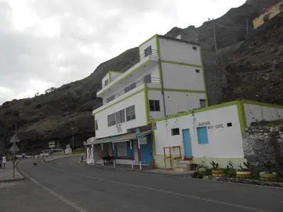 a building on the side of a road with a mountain at Guest House Frontera in Pinto