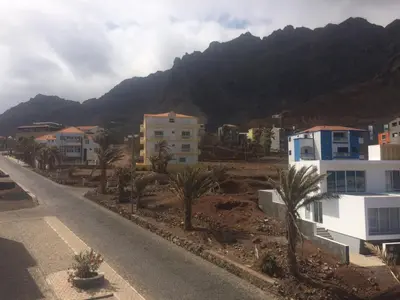 a street with houses and palm trees and a mountain at Sissi's B&B in Ponta do Sol