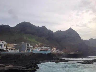 a group of houses on a rocky shore with mountains at Sissi's B&B in Ponta do Sol