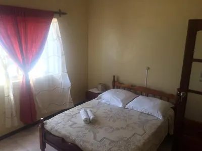 a bedroom with a bed with a red curtain and a window at Sissi's B&B in Ponta do Sol