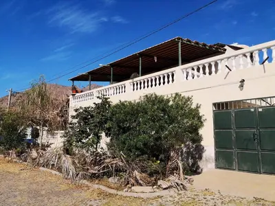 a white building with a green garage door and a tree at Casa Tabanka Apartment in Tarrafal