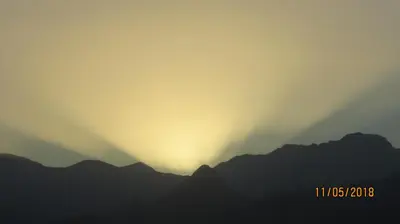 a sunset over a mountain range with the sun setting at Casa Branca in Porto Novo