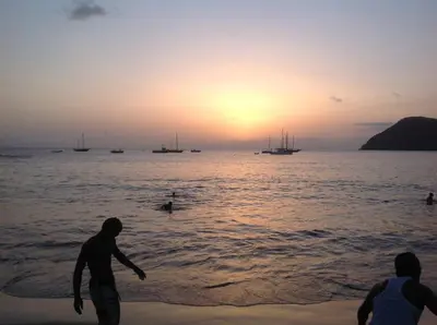 two people playing in the water on the beach at sunset at Casa Cabral : Big Apartment next to the beach in Tarrafal